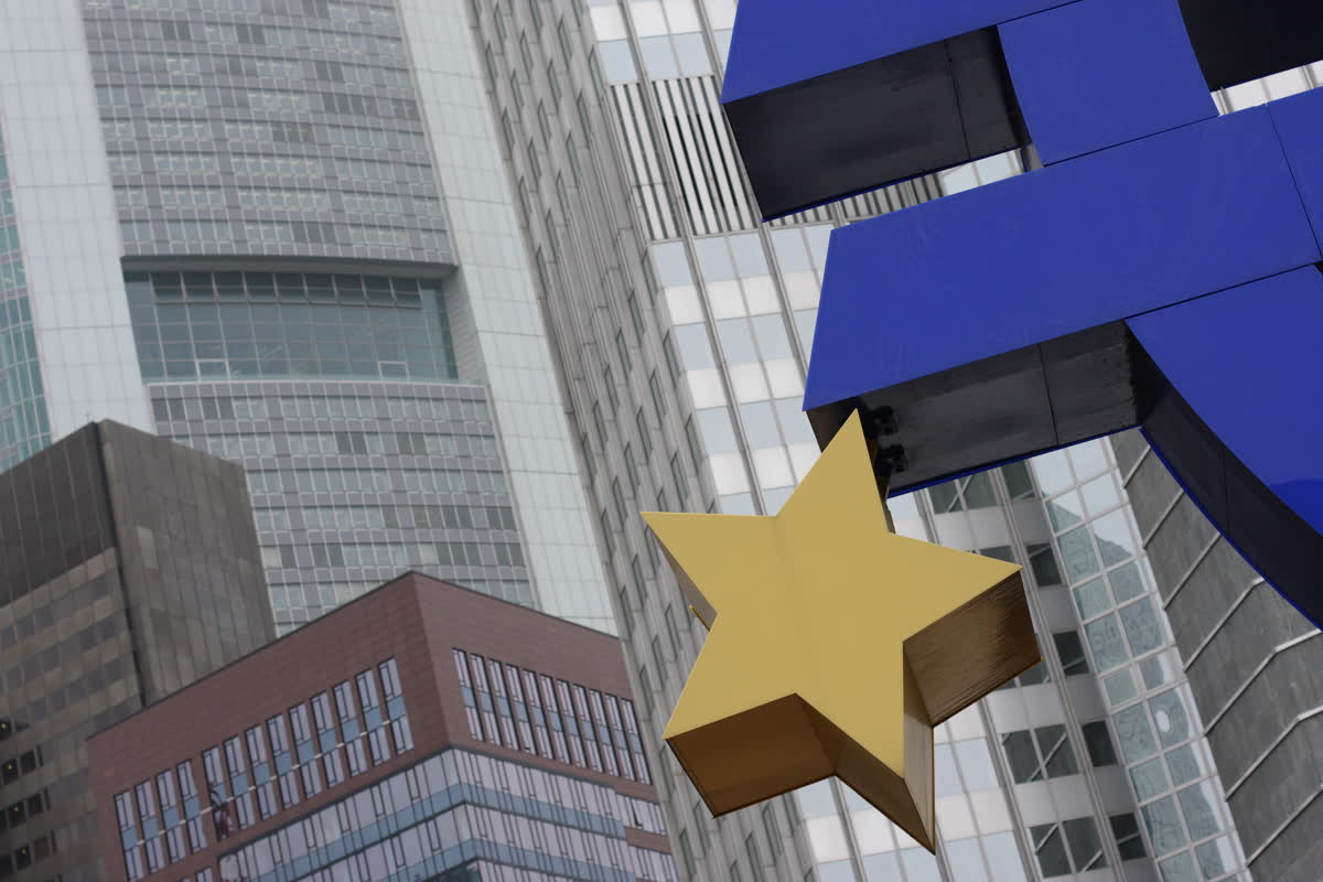 Frankfurt'ta cam cepheli yüksek ofis binalarının önünde duran büyük mavi avro simgesi heykeli ve sarı yıldız