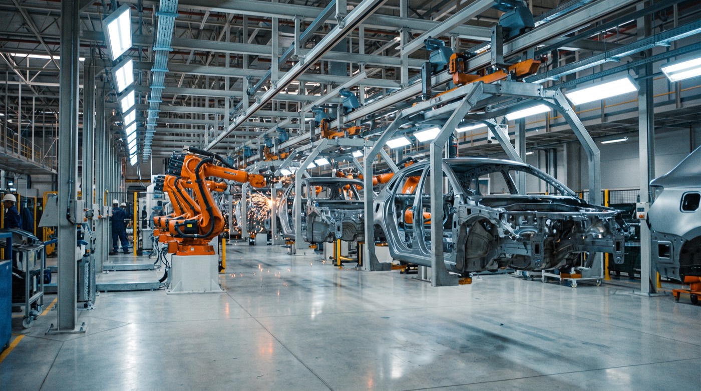 Otomobil fabrikasının gövde hattı; turuncu robot kolları kaynak yaparken